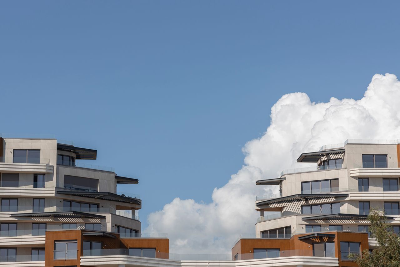 The Art of Drawing Readers In: Your attractive post title goes here Contemporary urban architecture under a bright blue sky with clouds.
